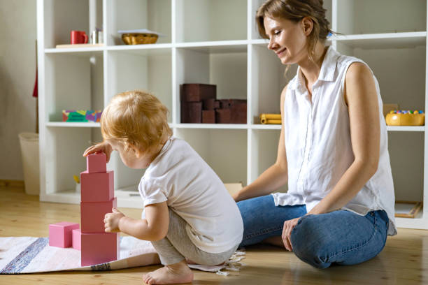 joven madre y pequeño bebé ensamblando cubo rosa maria montessori materiales ecológicos - cube baby child block fotografías e imágenes de stock