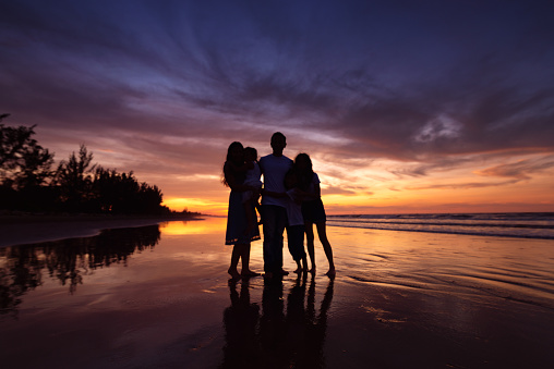 Silhouettes of happy family on beach during sunset