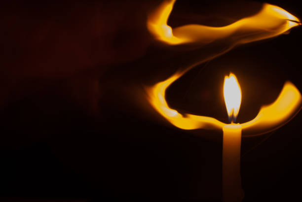 istock Blurred candlelight, front view with light of candle flame blowing in the wind on black background. Ideas for Halloween, Christmas, Home, Romance, Love, Copy space for you 1355000867