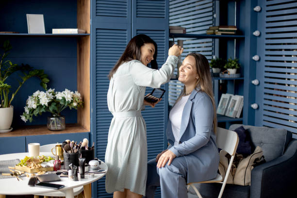 istock Professional female makeup artist applying cosmetics on model face use brush working at beauty salon 1355003238