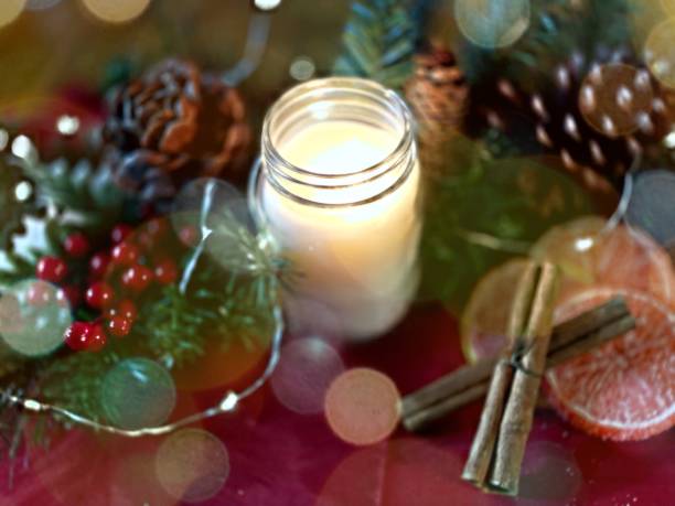 istock Bokeh light effect over berries and pine around scented candle with candied citrus and cinnamon sticks  - stock photo 1355006515