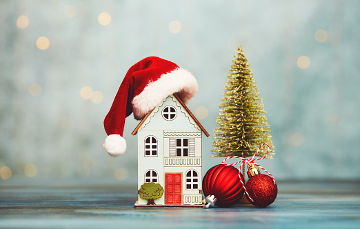 House with Santa hat and Christmas tree and holiday decorations. Home for the holidays theme