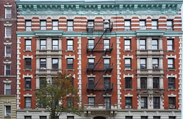 istock Old fashioned Manhattan apartment building facade with ornate roof cornice and external fire escape ladders 1355010195