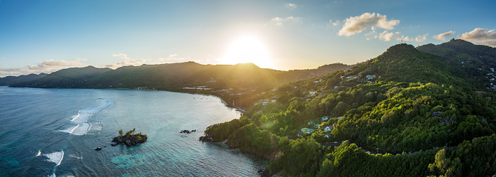 Seychelles Mahe Island Pointe Au Sel - Anse Royale Sunset Panorama View. Moody sunset over the coastal hill range of Pointe Au Sel - Anse Royale Beach and Lagoon. Stiched XXXL Panorama, Drone point of view along the beach, coast and islet. Pointe Au Sel,  Anse Royale, Mahé Island, Seychelles Islands, Africa