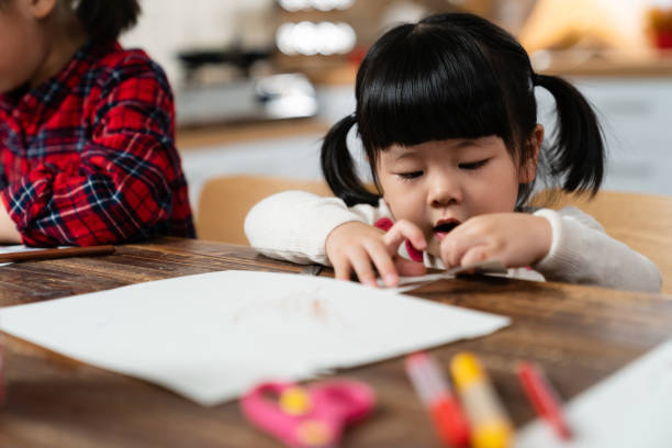 istock closeup with selective focus cute asian baby girl having fun doing paper craft while making preparation for Christmas and new year at table with her sister 1355014250