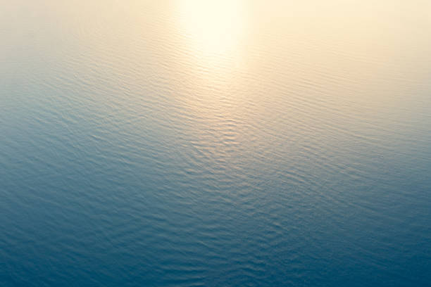 透き通った海水の質感の空中写真。自然な青の背景の上からのビュー。青い水の反射。夕暮れ時の青い海の波。夏の海。トップビュー - 静水 ストックフォトと画像