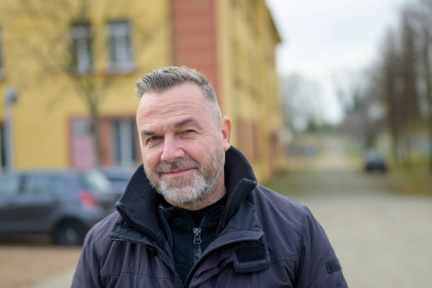 istock Middle-aged man standing in a town square looking at camera 1355019562