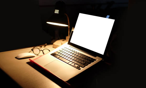 istock Computer laptop with blank screen and glowing lamp in dark room. 1355019627
