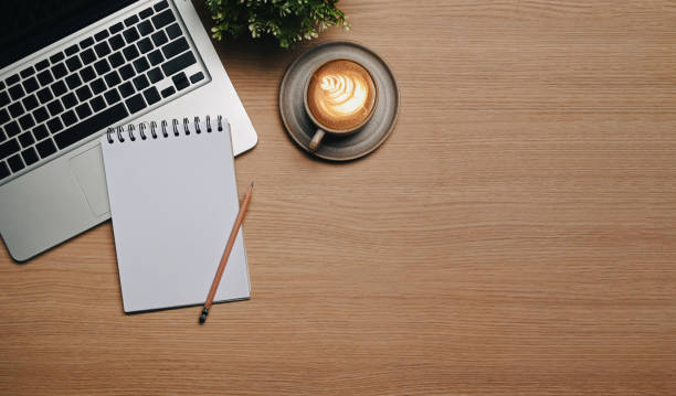 istock Empty notebook, laptop and cup of hot coffee on wooden desk. 1355022817