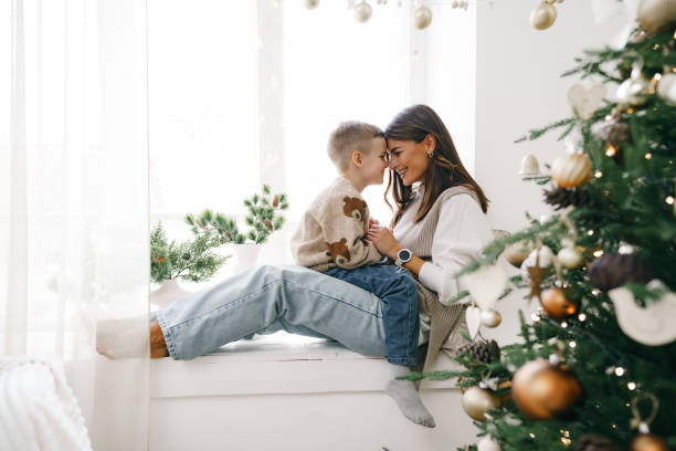 istock Happy mother with son sit on windowsill near Christmas tree 1355028642