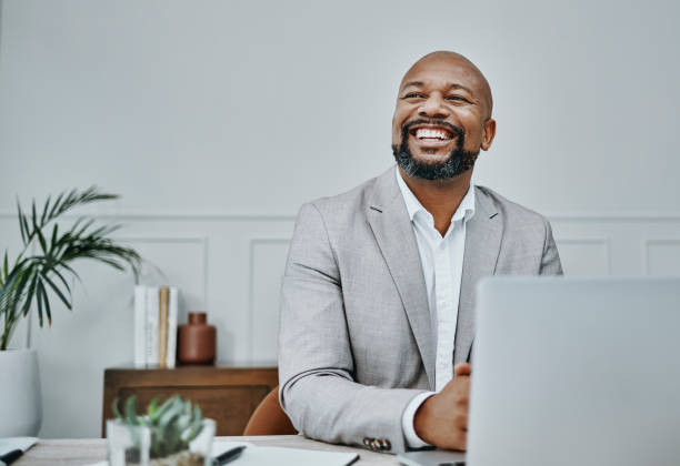 scatto di un uomo d'affari maturo che usa un laptop in un ufficio moderno - business businessman cheerful happiness foto e immagini stock