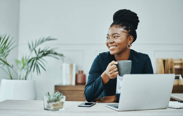 scatto di una giovane imprenditrice che usa un laptop e caffè in un ufficio moderno - thinking women businesswoman business foto e immagini stock