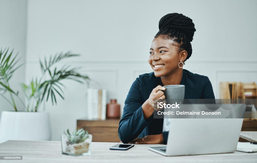 Shot of a young businesswoman using a laptop and having coffee in a modern office My empire, look how far we've come Women Stock Photo
