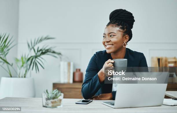 Shot Of A Young Businesswoman Using A Laptop And Having Coffee In A Modern Office Stock Photo - Download Image Now