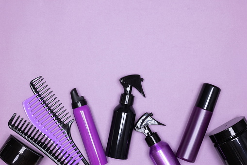 Hair care and styling products with combs layout on purple background. Copy space