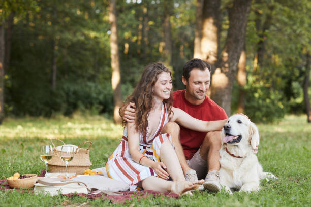 istock Couple Enjoying Picnic Outdoors with Dog 1355031577