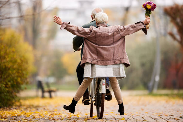 秋の日に自転車で楽しんでいるシニアカップルの背面図。 - senior adult fun autumn senior couple ストックフォトと画像