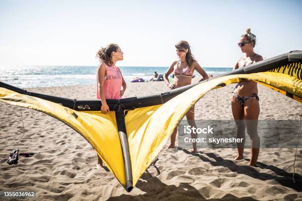 Group Of Young Women Talking While Preparing For Kitesurfing On The Beach Stock Photo - Download Image Now