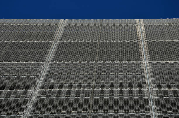 istock steel cladding of a building with a expanded metal lattice structure. galvanized gray nets protect the industrial building. Blue sky in contrast to a silver background 1355037608