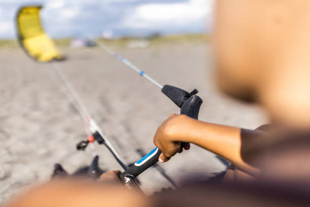 Close up of unrecognizable woman holding kitesurfing equipment at the beach.