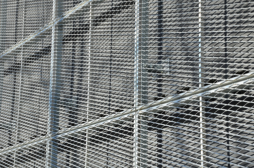 steel cladding of a building with a expanded metal lattice structure. galvanized gray nets protect the industrial building. Blue sky in contrast to a silver background, expanded, metal