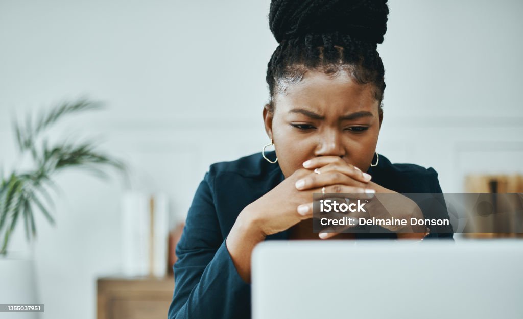 Shot of a young businesswoman frowning while using a laptop in a modern office There has to be a way out of this Confusion Stock Photo