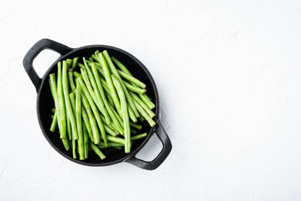 Green french beans cooking, in frying cast iron pan, on white stone  background, top view flat lay, with copy space for text Green french beans cooking set, in frying cast iron pan, on white stone  background, top view flat lay, with copy space for text runner bean stock pictures, royalty-free photos & images