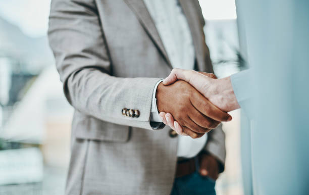 Shot of a businessman and businesswoman shaking hands in a modern office stock photo