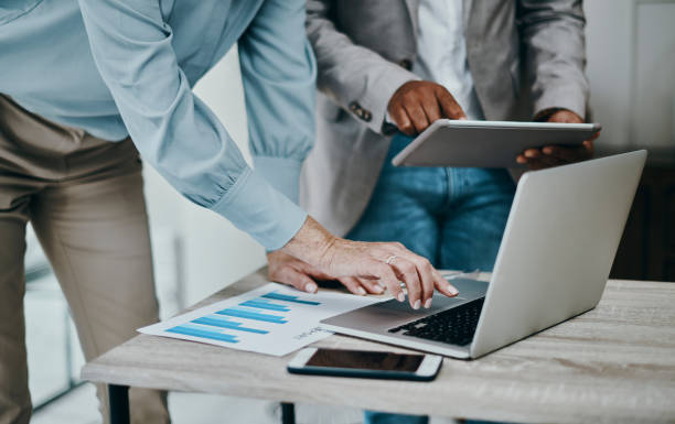 Shot of a businessman and businesswoman using a laptop and digital tablet during a meeting in a modern office Meetings work with teamwork african descent analyzing business white stock pictures, royalty-free photos & images