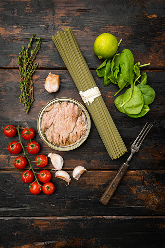 Uncooked Pasta with vegetables and tuna ingredients set, on old dark  wooden table background, top view flat lay