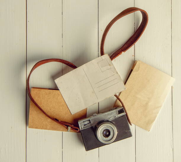 istock Old film retro camera and several blank backgrounds on rough wooden table 1355040144
