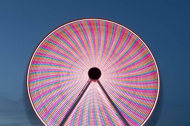 grande roue lumineuse - ferris wheel wheel blurred motion amusement park photos et images de collection