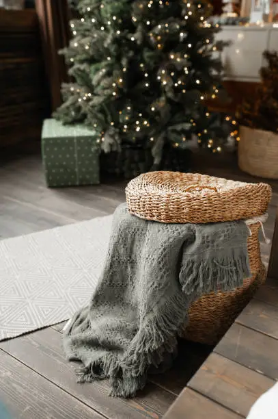 Wicker straw basket for storing clothes on boho-style bedroom with wicker baskets and wooden shelves. grey Christmas interior natural eco-components. vertical content, selective focus