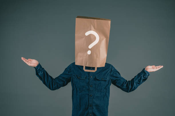 istock A young man has a paper bag on his head with a question mark, asking why, looking for answers, dark background 1355045959