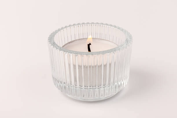 istock Burning tea candles in a glass holder, isolated on white. Space for text 1355046040