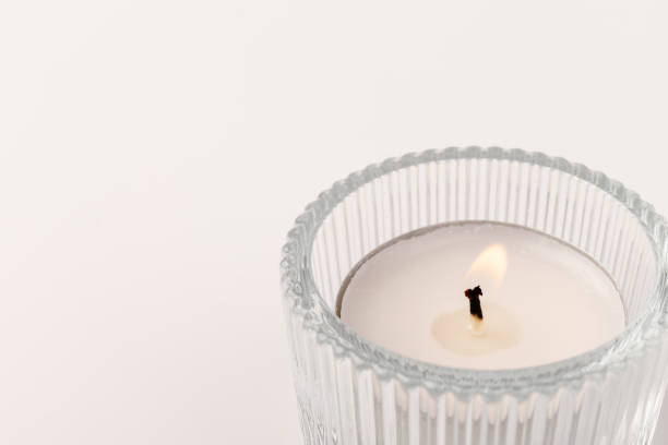 istock Burning tea candles in a glass holder, isolated on white. Space for text 1355046047