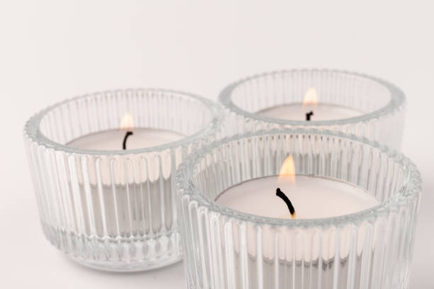 istock Burning tea candles in a glass holder, isolated on white. Space for text 1355046062