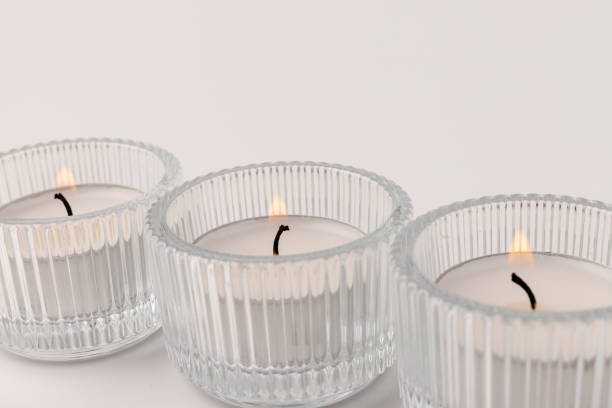 istock Burning tea candles in a glass holder, isolated on white. Space for text 1355046071
