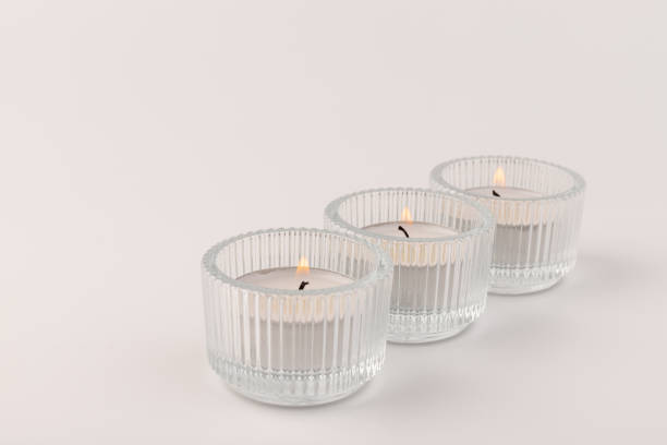 istock Burning tea candles in a glass holder, isolated on white. Space for text 1355046081