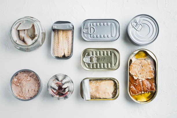 Canned fish with different assortment types of seafood, on white background, top view flat lay