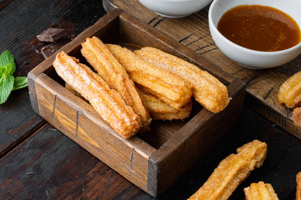 istock Churros sprinkled with powdered sugar, on old dark  wooden table background 1355048747