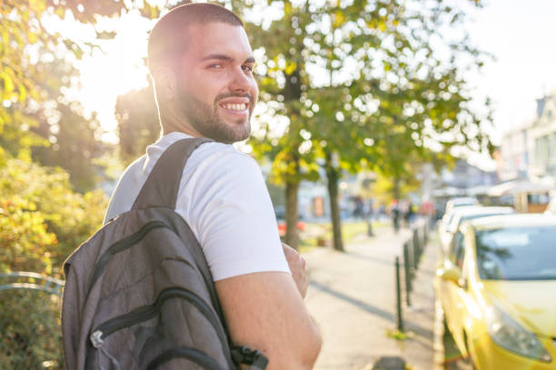 istock Smiling male student with a backpack leaving down the street 1355051116