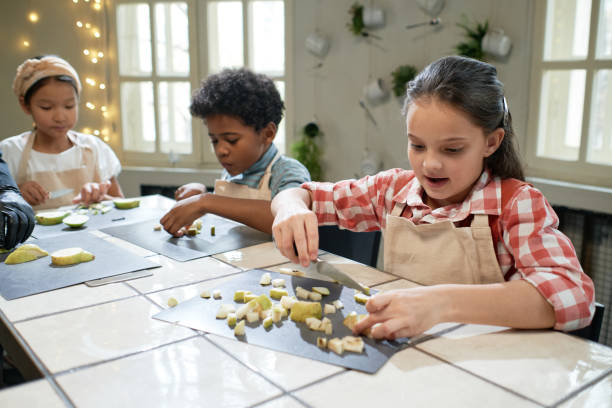 istock Children cutting fruits at the table 1355052796
