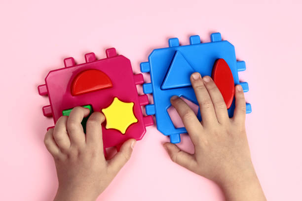 istock child plays an educational constructor on a pink background, hands close-up 1355053354