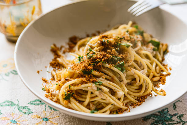 homemade italian pasta dish known as "pasta con le sarde" on table cloth, made with spaghetti, sardines, parsley, pine nuts and breadcrumbs. Classic italian regional cuisine. stock photo