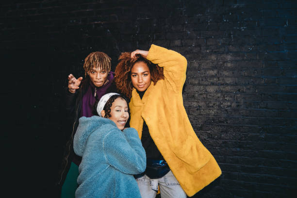 drei freunde tanzen in der stadt gegen eine schwarze backsteinmauer - hip hop hipster afro men stock-fotos und bilder