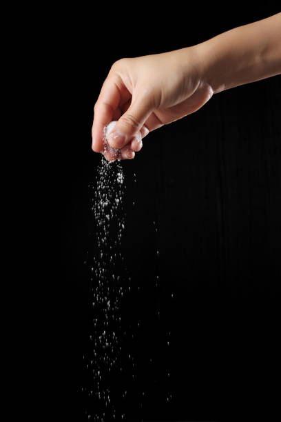 istock Hand sprinkling sugar isolated on black background 1355054837