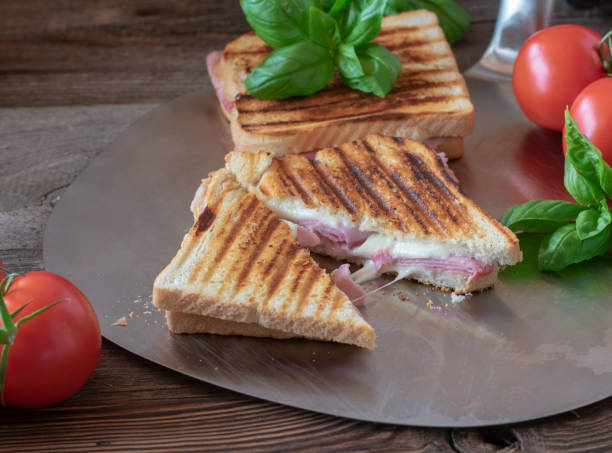 Ham and cheese sandwich with mozzarella Delicious fresh grilled ham and cheese sandwich with melted mozzarella served with basil leaf on wooden table ham and cheese sandwich stock pictures, royalty-free photos & images
