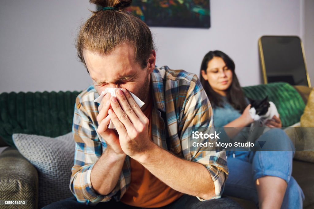 Plan recadré d’un beau jeune homme se faisant le nez à la maison avec sa petite amie en arrière-plan - Photo de Allergie libre de droits Plan recadré d’un beau jeune homme se faisant le nez à la maison avec sa petite amie en arrière-plan - Photo de Allergie libre de droits