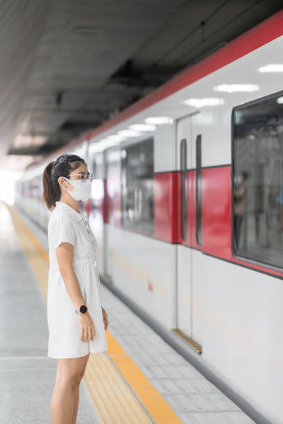 istock woman wearing Protective face mask prevention coronavirus inflection during waiting train. public transportation. social distancing, new normal and safety under covid-19 pandemic 1355056434